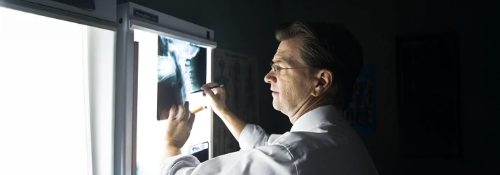 Dr. Scott Shepard D.C. in a white coat reviewing and marking an X-ray image on a lightbox.